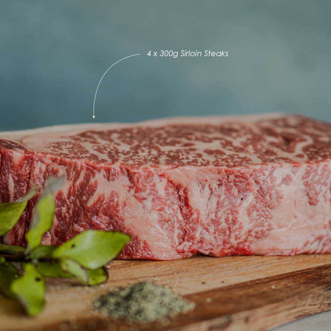 Block of raw sirloin steak on a wooden board with text indicating weight.