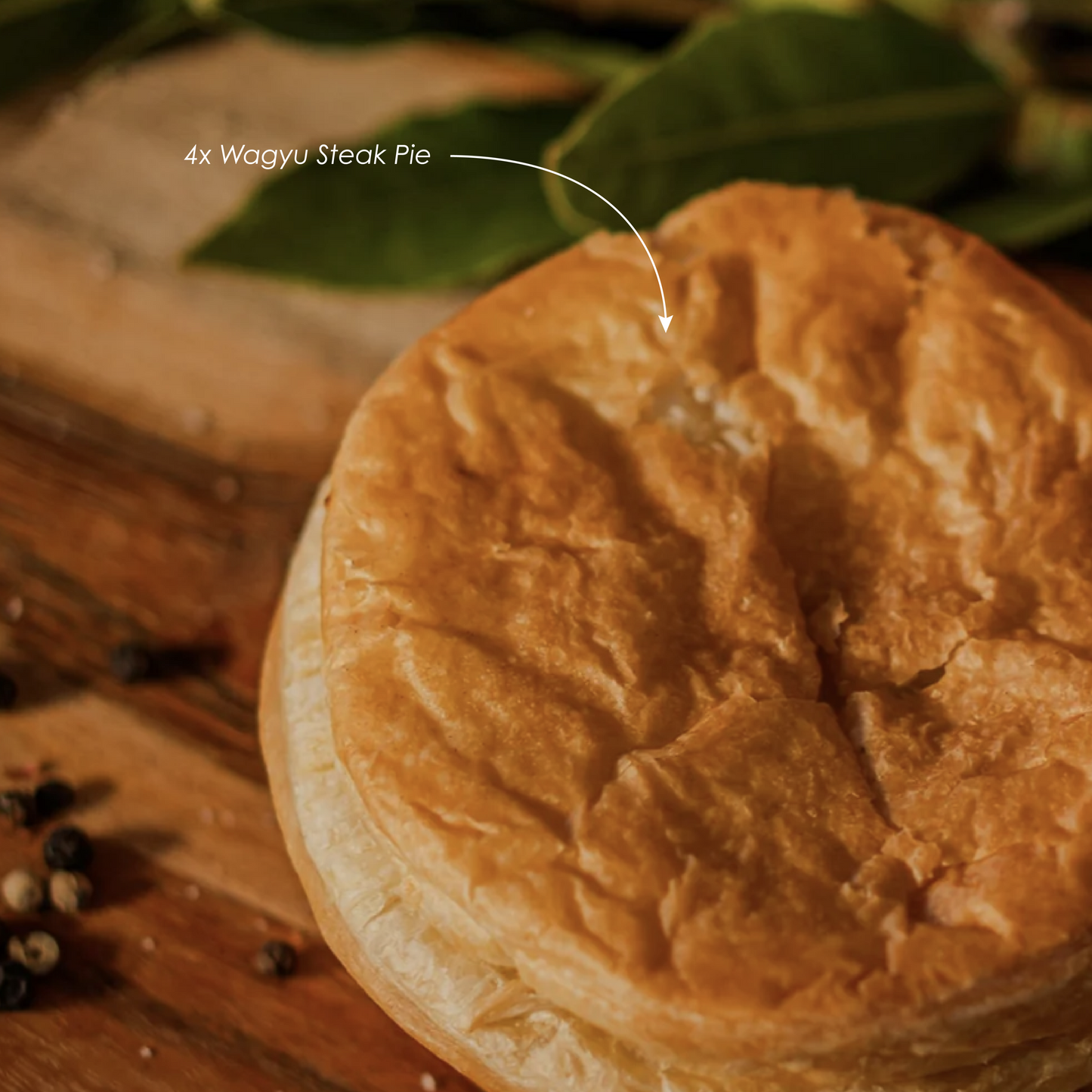 Wagyu steak pie on a wooden board with bay leaves in the background