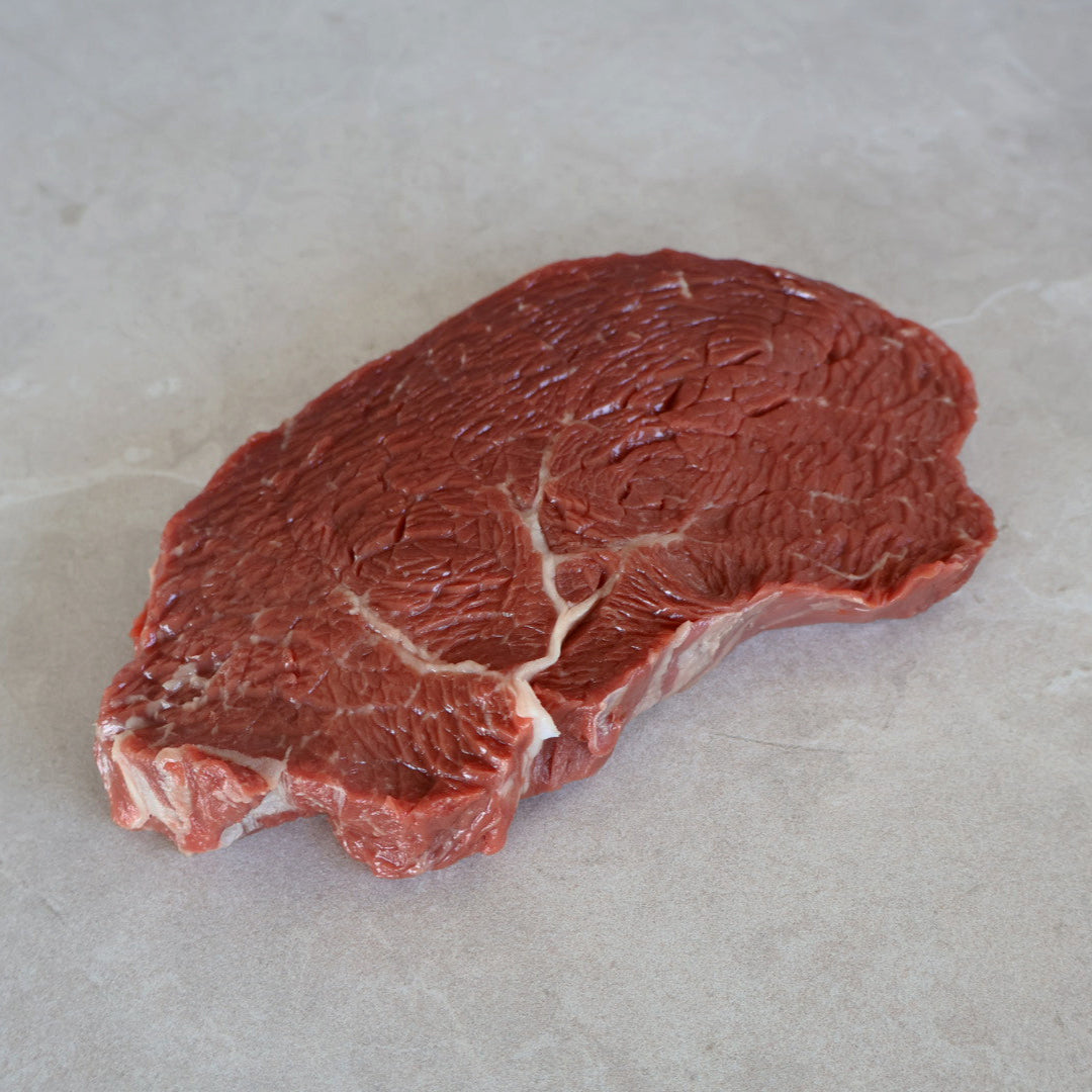 Raw wagyu rump steak on a light gray surface