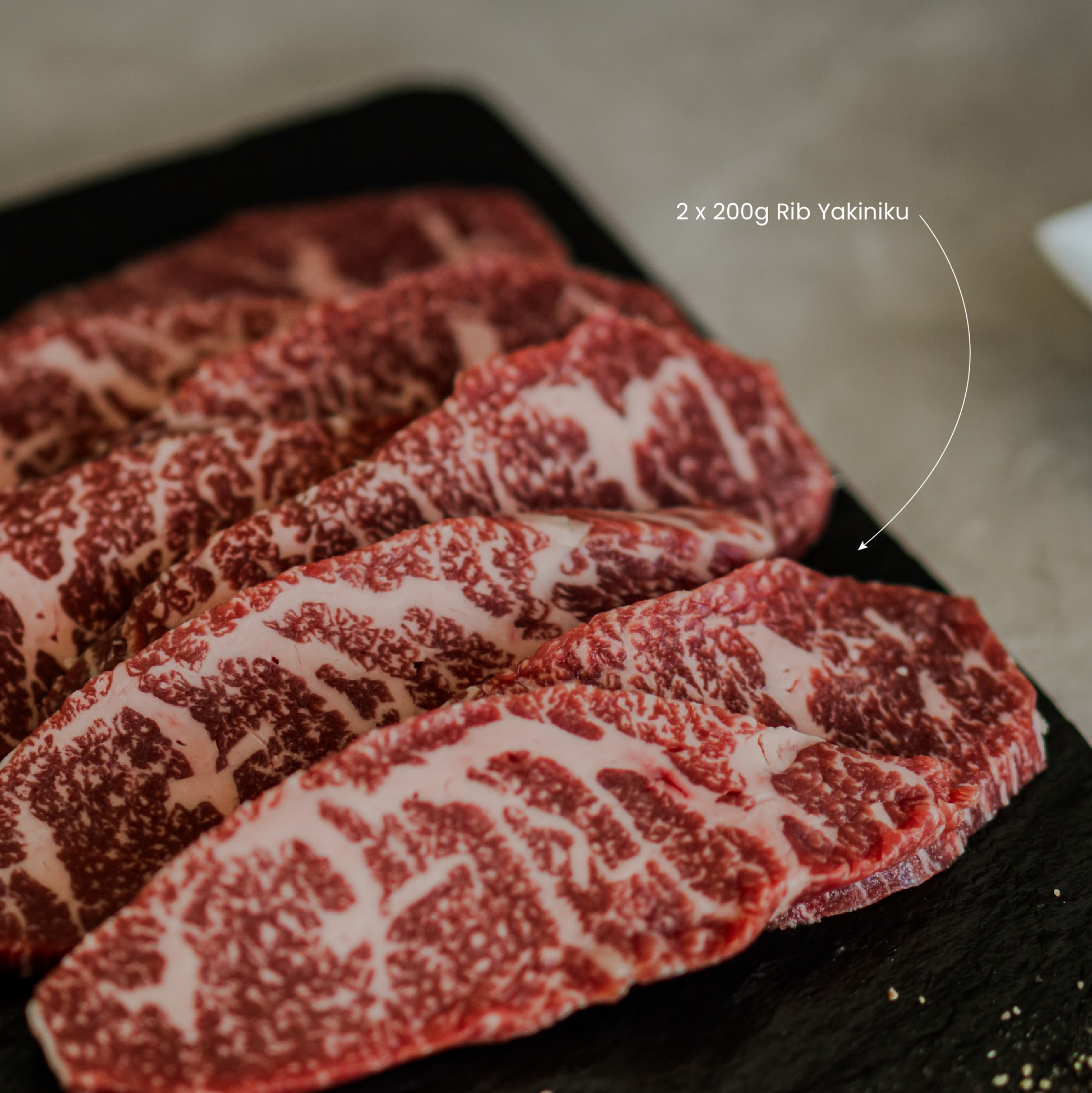  Yakiniku slices of marbled wagyu beef on a black tray with visible text.