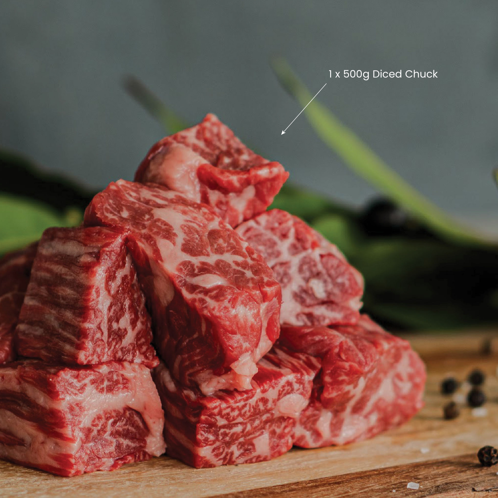 Stack of diced wagyu beef on a wooden board with a blurred background