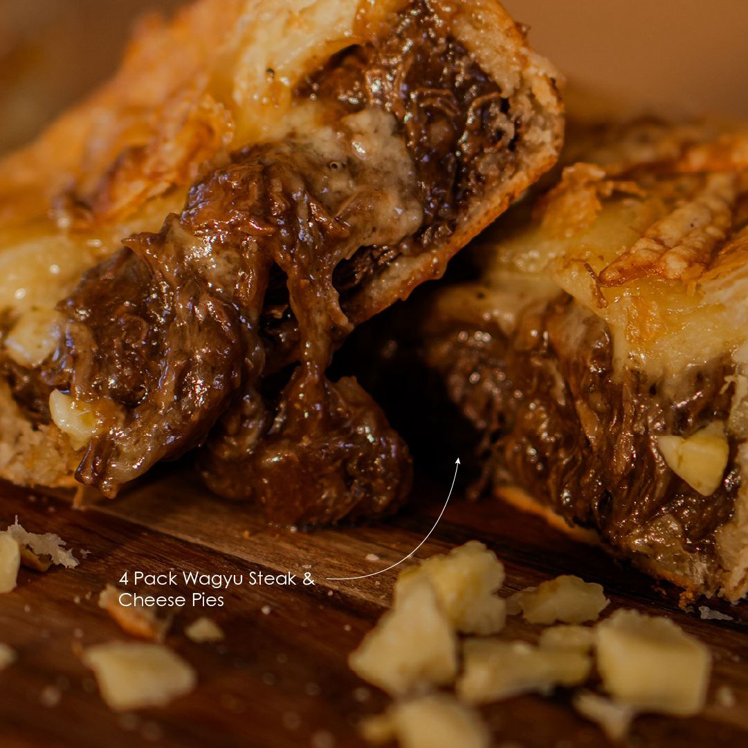 Close-up of a sliced Wagyu Steak & Cheese Pie on a wooden board.