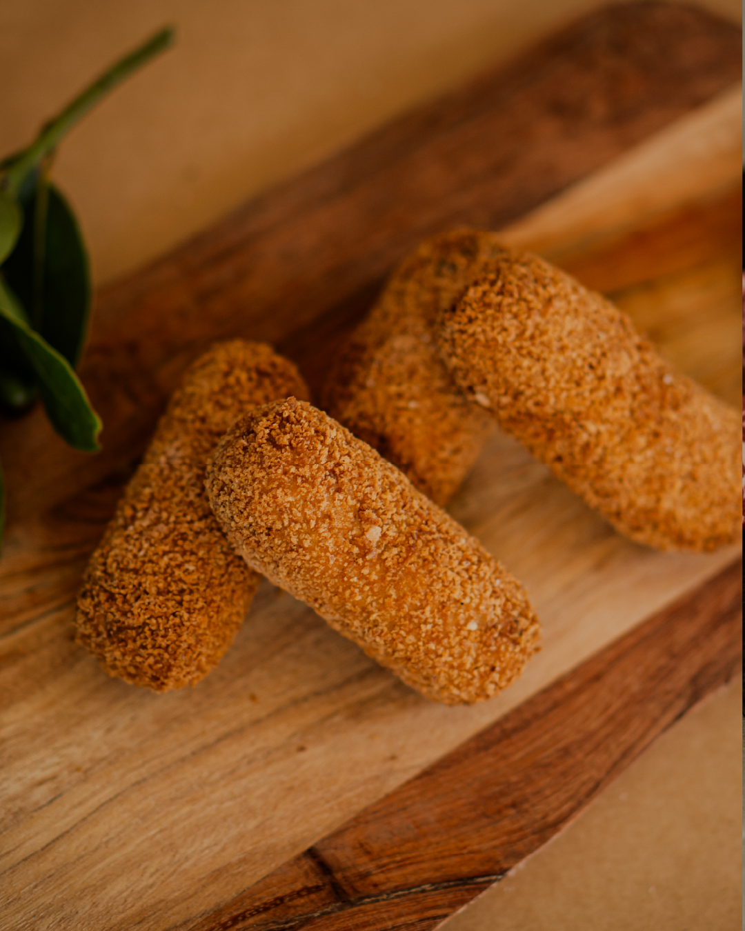 Three breaded croquettes on a wooden surface