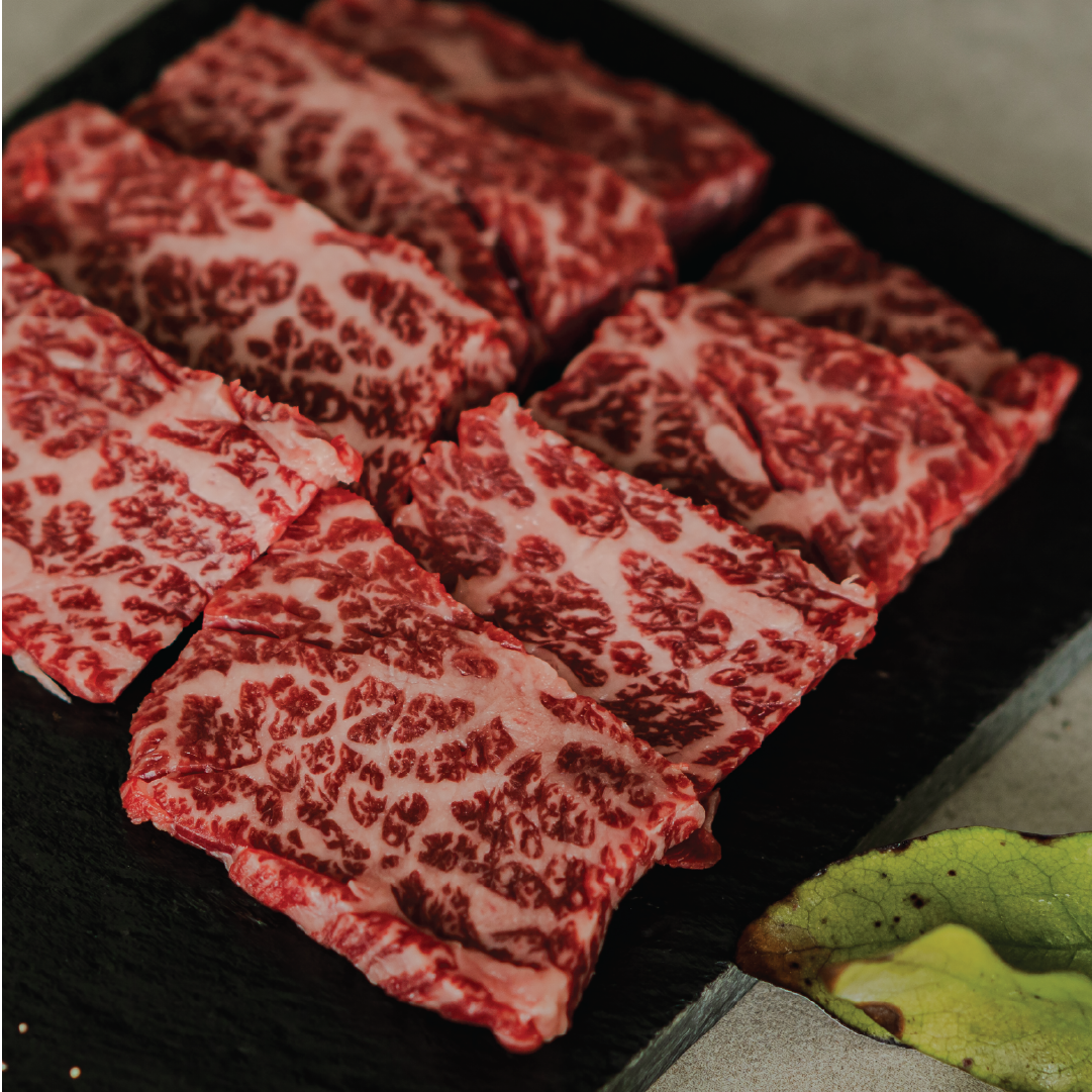 Raw marbled beef slices on a black stone surface