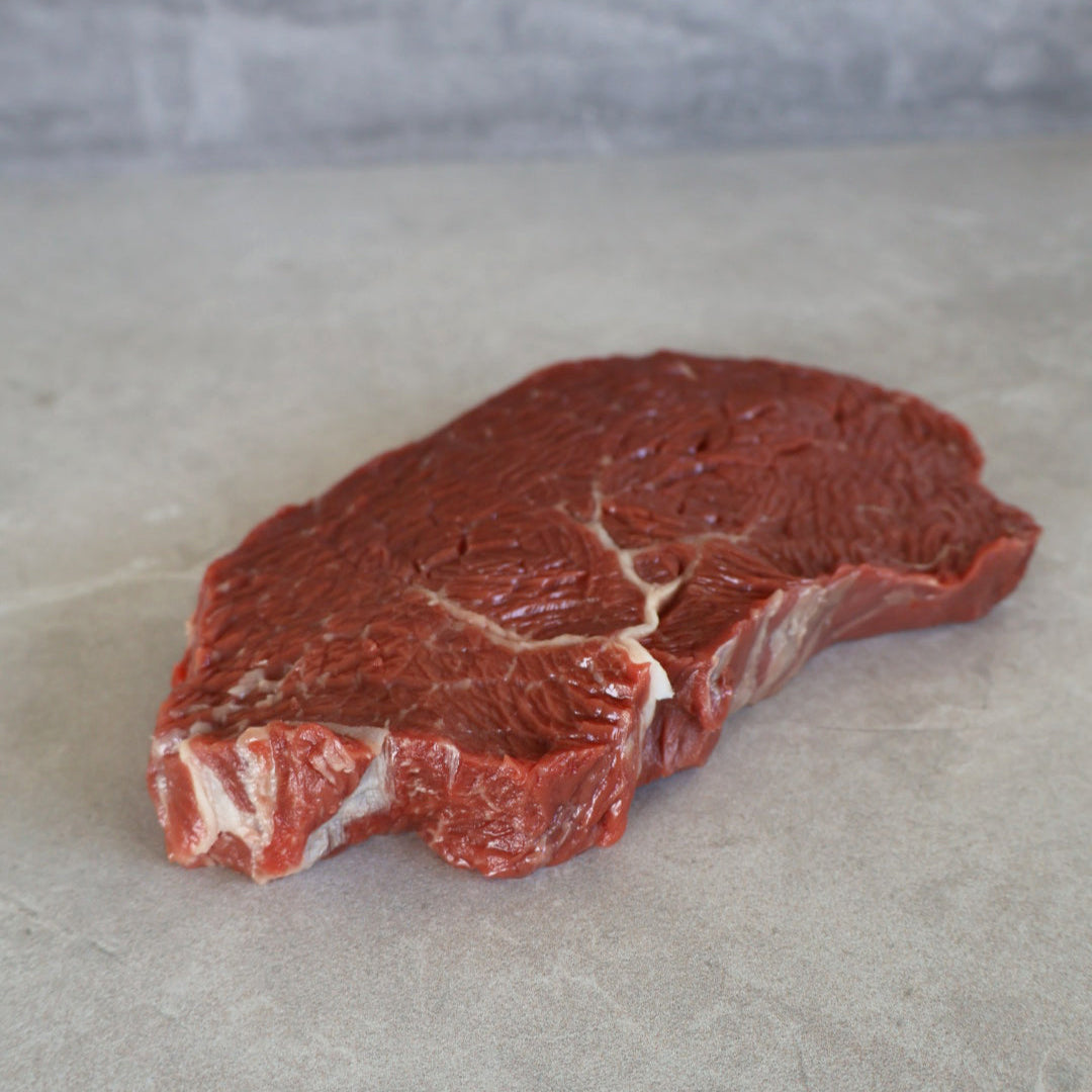 Raw wagyu rump steak on a gray surface with a gray background