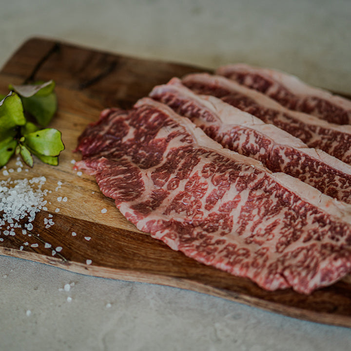 Black Origin wagyu beef shabu-shabu slices laid on a wooden board with decorative garnish